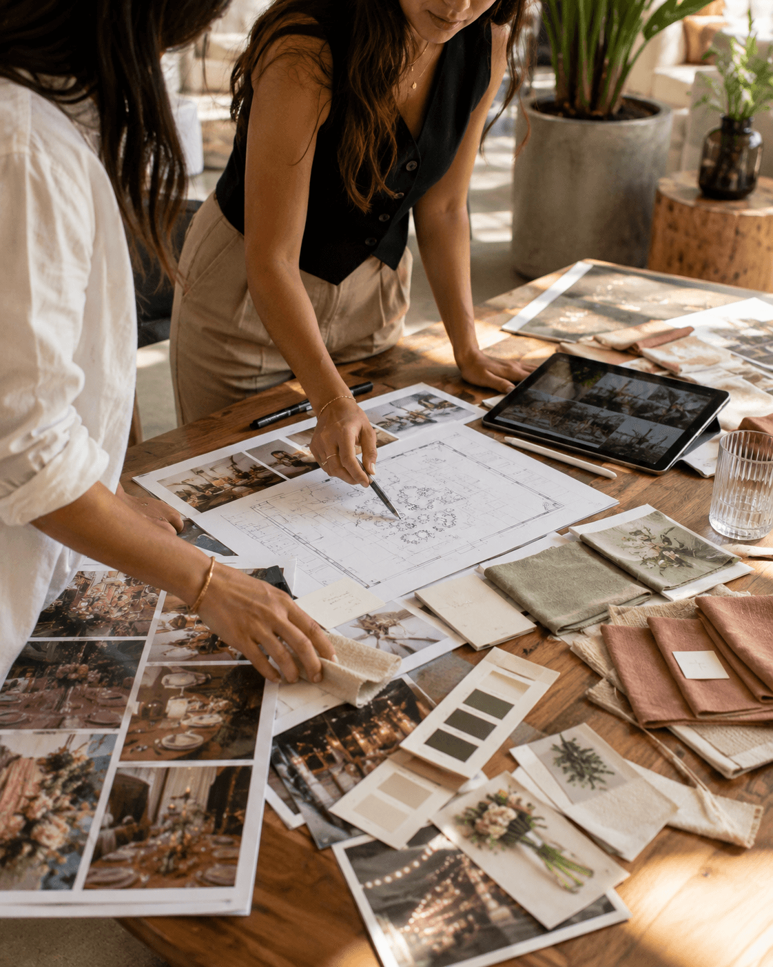 Two planners shaping the concept together over a floor plan, fabric swatches and a tablet